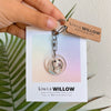 Keychain with a dog's face on a card held by a hand, with 'kiwi & Willow' branding.
